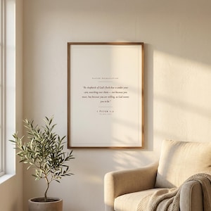 Pastor appreciation Christian wall art print featuring 1 Peter 5:2 Be shepherds of God's flock in elegant serif typography on cream paper. Framed in walnut wood above a beige armchair beside an olive tree in warm light. Minimalist scripture decor and thank you gift for a pastor, minister or church leader. Instant digital download printable.