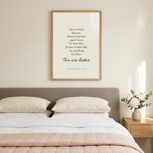 Ecclesiastes 4:9-10 'Two Are Better Than One' wedding scripture print in oak frame above the headboard of a newlywed bedroom with white linen, blush throw, and white peonies. Christian wedding wall art for bedroom, newlywed gift, first anniversary, engagement present, instant digital download.