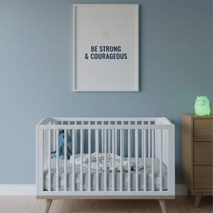 Be Strong and Courageous Joshua 1:9 Wall Art Christian Boys Room Print Scripture — shelf mockup leaning on wood shelf with decorative items. This elegant christian scripture wall art print features beautiful serif typography on warm cream background. Joshua 1:9 bible verse digital download printable for home office bedroom living room gallery wall decor. Perfect christian gift idea from TheFram...