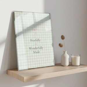 Sage coquette christian wall art print in thin black wood frame on glass shelf beside sage eucalyptus stems and white ceramic vase, warm golden light reflection, shelf_glass sage bible print godly wall art coquette scripture digital download aesthetic christian TheFramedVerse dorm room bundle