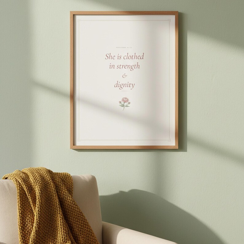 She Is Clothed in Strength and Dignity Proverbs 31 25 Wall Art Coquette Christia — front facing framed mockup on clean white wall with shadow. This coquette bow, botanical, pink blush christian scripture wall art print features beautiful serif typography on warm cream background. Proverbs 31 25 bible verse digital download printable for home office bedroom living room gallery wall decor. Perfec...