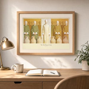 Desk mockup of The Wedding at Cana in a light oak frame above a wooden workspace with a brass lamp, ceramic mug, open notebook, pen, and leafy plant. The artwork shows Christ centered between six complete stone jars, with three on the left and three on the right. Angled sunlight, neutral styling, and cream matting place the Bible story print in a quiet study or home office setting.