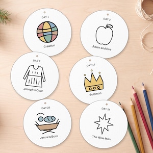Può includere: Sei ornamenti circolari bianchi con illustrazioni a linee nere e testo. I disegni includono Day 1 Creation, Day 2 Adam and Eve, Day 7 Joseph's Coat, Day 13 Solomon, Day 24 The Wise Men e Day 25 Jesus is Born con accenti colorati.
