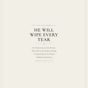 Hero view of the framed design, clearly showing the verse lettering, balanced spacing, and refined color palette. The He Will Wipe Every Tear artwork presents Revelation 21:4 in minimalist black typography on warm beige. This Revelation 21:4 print suits a sympathy gift, memorial space, prayer room, bedroom, or comforting Christian home as printable digital wall art.