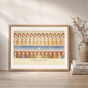 Leaning frame mockup of The Shepherds and the Angels on a rustic wood console beside stacked art books and a tall ceramic vessel with dried stems. The print shows a row of angels above shepherds and their sheep, with a star set between the two groups. The oak frame, broad cream mat, plaster wall, and soft side light create a relaxed display while keeping the title and Luke 2:13 legible.