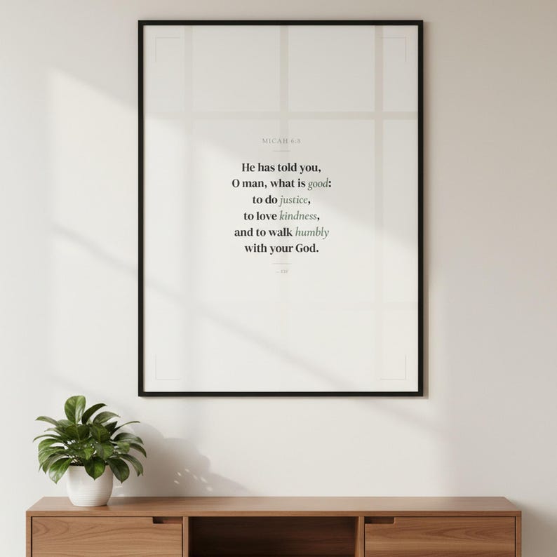 Micah 6:8 wall art hanging in black glass frame on warm white living room wall above mid-century console with plant. He has told you O man what is good to do justice to love kindness and to walk humbly with your God ESV. Sage green scripture print Christian Father Day graduation confirmation gift. Digital download printable bible verse for home office study bedroom gallery wall decor from TheFramedVerse