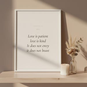 Love Is Patient Love Is Kind 1 Corinthians 13:4 Wall Art Christian Wedding, in romantic wedding typography with elegant calligraphy, delicate gold ornamental accents on warm blush background, hanging above a cozy bed in a peaceful bedroom setting with soft linens and warm lighting, creating an inspiring and calming atmosphere perfect for morning devotions and evening prayer