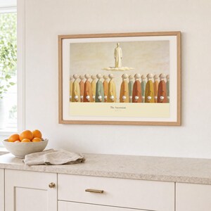 Kitchen mockup of The Ascension framed in light oak above a pale stone counter, white cabinetry, a linen cloth, and a bowl of oranges. The artwork shows Christ standing in light above a soft cloud while gathered witnesses look upward. Bright window light and the warm cream mat demonstrate how the Christian print works in a clean, welcoming kitchen interior.