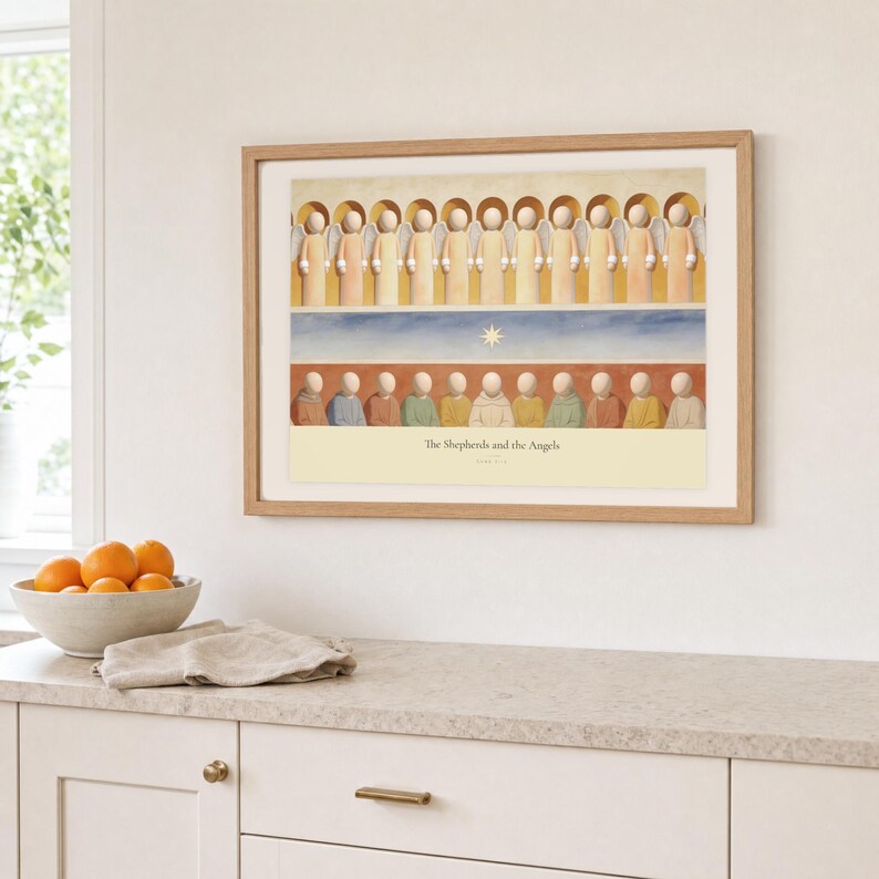 Kitchen mockup of The Shepherds and the Angels framed in light oak above a pale stone counter, white cabinetry, a linen cloth, and a bowl of oranges. The artwork shows a row of angels above shepherds and their sheep, with a star set between the two groups. Bright window light and the warm cream mat demonstrate how the Christian print works in a clean, welcoming kitchen interior.