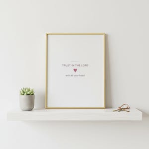 Trust in the Lord With All Your Heart Proverbs 3:5 Wall Art Pink Blush Coquette  — shelf mockup leaning on wood shelf with decorative items. This coquette bow, pink blush christian scripture wall art print features beautiful serif typography on warm cream background. Proverbs 3:5 bible verse digital download printable for home office bedroom living room gallery wall decor. Perfect christian gif...
