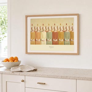 Kitchen mockup of Pentecost framed in light oak above a pale stone counter, white cabinetry, a linen cloth, and a bowl of oranges. The artwork shows a row of faceless apostles standing shoulder to shoulder, each with a small flame above the head. Bright window light and the warm cream mat demonstrate how the Christian print works in a clean, welcoming kitchen interior.