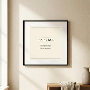 Doxology Praise God From Whom All Blessings Flow christian hymn art print in thin black frame with white mat on warm cream linen wall, soft natural window light and gentle shadow, dark forest green Cormorant Garamond serif typography on cream, minimalist doxology wall art hero product shot baptism wedding