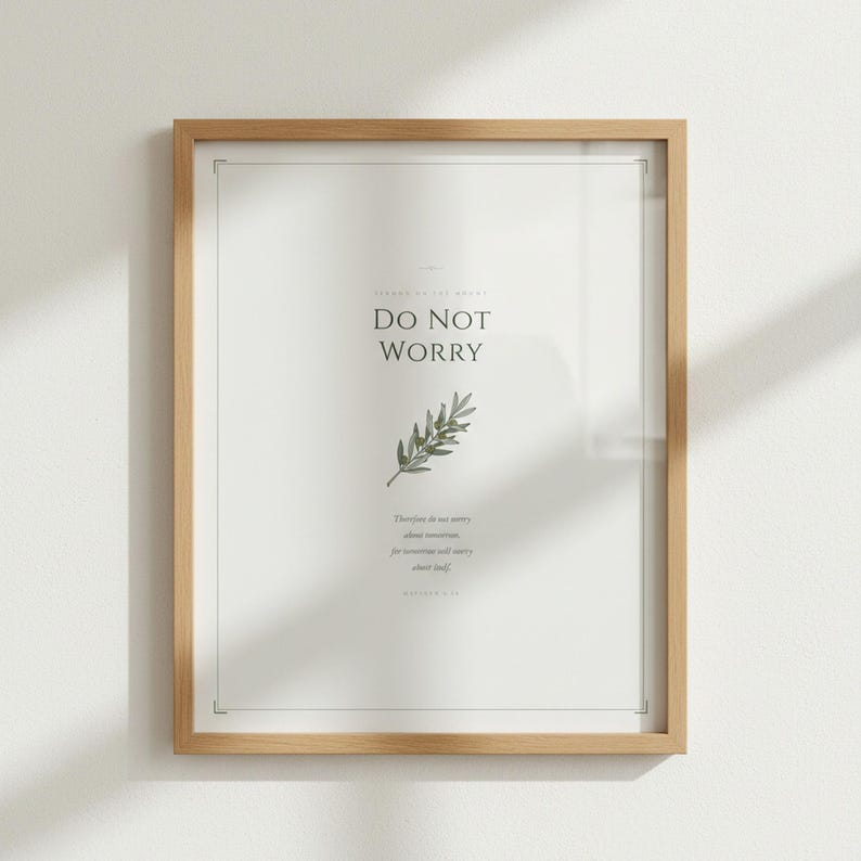 Do Not Worry Matthew 6:34 sage green scripture print in light wood frame, frontal white background product shot, crystal-clear serif typography on cream linen paper texture, elegant bible print botanical minimalist christian wall art, TheFramedVerse digital download, godly wall art baptism gift idea