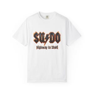 May include: A white ceramic mug with a black handle and the text "But First, Coffee" in a bold, black font. The mug is set against a blurred background, suggesting a cosy setting.