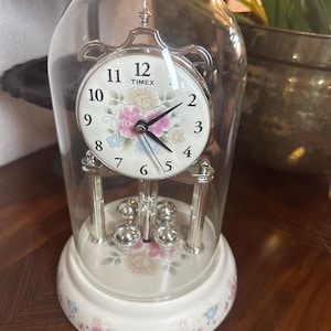 Vintage Timex anniversary clock with a floral base and glass dome, silver accents
