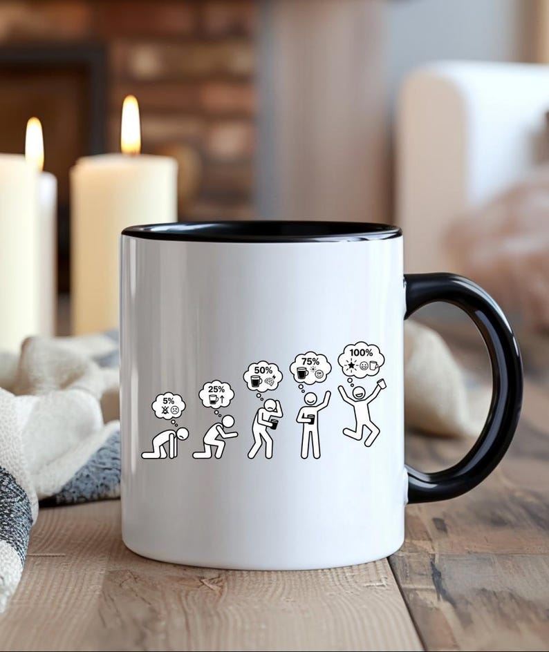 K&ouml;nnte beinhalten: Wei&szlig;e Keramik-Kaffeetasse mit schwarzem Innenraum und Griff. Die Tasse zeigt eine schwarz-wei&szlig;e Grafik, die das Energieniveau einer Person von 5 % bis 100 % darstellt, mit Kaffee und einer Gl&uuml;hbirne in Gedankenblasen. Die Tasse steht auf einer Holzoberfl&auml;che.