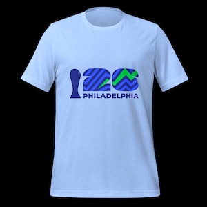 May include: Light blue t-shirt with a graphic design. The design features the number "126" in blue and green, with the word "PHILADELPHIA" below in navy blue. The shirt is a crew neck style.