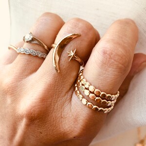 Op de afbeelding: Een set gouden ringen met een halve maan met een sterontwerp en een stapel van drie kralenringen.