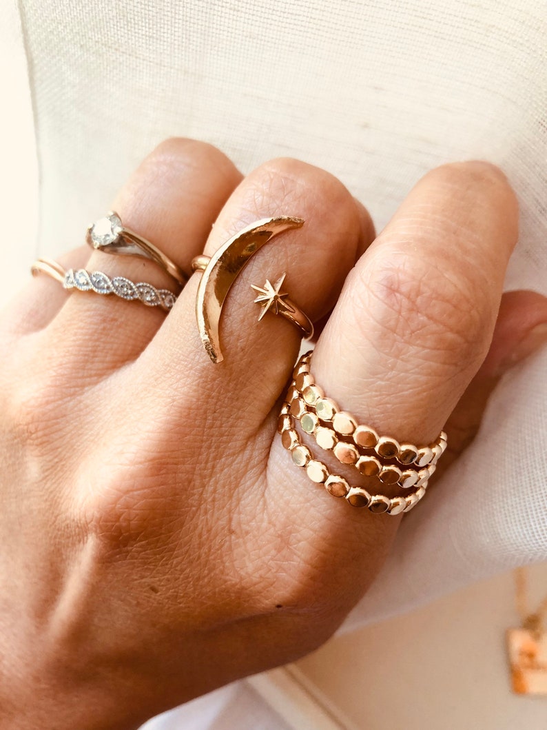 Op de afbeelding: Een set gouden ringen met een halve maan met een sterontwerp en een stapel van drie kralenringen.