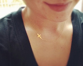 May include: A delicate gold chain necklace with a small, simple cross pendant.