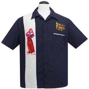 Puede incluir: Una camisa de bolos azul marino con una franja blanca en la parte delantera. El lado izquierdo de la camisa presenta una imagen de dibujos animados de una mujer con un vestido rojo. El lado derecho de la camisa tiene un logotipo dorado que dice "The Ink & Paint Club".