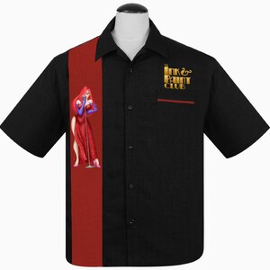Puede incluir: Camisa negra de manga corta con botones y una raya roja en el lado izquierdo. El lado derecho presenta un gr&aacute;fico dorado de una mujer con un vestido rojo y el texto "The Ink & Paint Club".