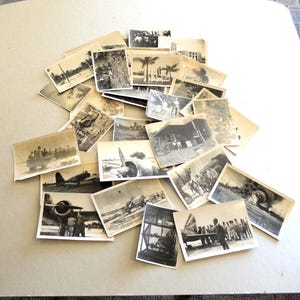 May include: A pile of monochrome photographs showing military aircraft, personnel, and tropical scenes. The images, in various sizes, depict wartime activities, including aircraft and personnel in tropical locations.