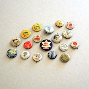 May include: A collection of seventeen circular pinback badges featuring various designs, including portraits, floral illustrations, and text such as Road Ranger, Stewart House, and Hospital Saturday Appeal, in assorted colours like red, blue, yellow, and white.