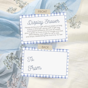 Op de afbeelding: Twee displaykaarten voor een babyshower met een blauwe ruitjesrand. De voorkant leest "Display Shower" en geeft instructies voor gasten. De achterkant heeft ruimtes voor "Aan" en "Van" met een lichtblauwe achtergrond.