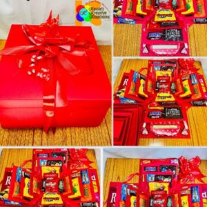 Può includere: Una scatola sorpresa rossa con un grande fiocco rosso. La scatola è piena di varie barrette di caramelle e dolcetti. Il testo "Sweet Surprise Explosion Box" è in alto nell'immagine.