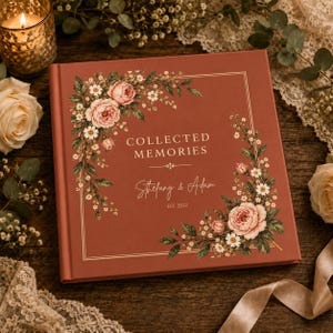 May include: A square photo album with a terracotta cover featuring gold foil text that reads COLLECTED MEMORIES, Stefany & Adam, and EST. 2022. The cover is decorated with a floral border of pink roses and white daisies in two corners.