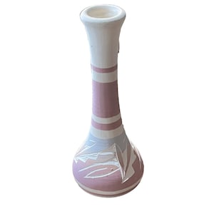 Puede incluir: Un jarrón de cerámica hecho a mano en blanco, rosa y azul claro. El jarrón tiene una base bulbosa con diseños de hojas talladas y un cuello largo y delgado con rayas rosas y blancas. La parte superior es blanca.