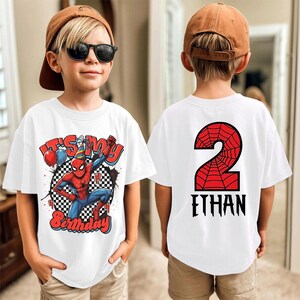 May include: White t-shirts with a Spider-Man theme. The front shirt features the text "It's My Birthday" with Spider-Man and balloons. The back of the shirt has a red number 2 with a spiderweb design and the name "Ethan" in black.