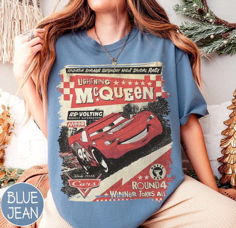 May include: Blue jean-colored t-shirt featuring a graphic of Lightning McQueen from the Disney Pixar Cars movie. The design includes text that reads "Radiator Springs Saturday Night Special Race" and "Winner Takes All."