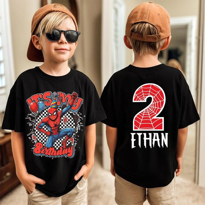 May include: Black t-shirt featuring a Spider-Man graphic with the text "It's My Birthday" and a checkered background. The back of the shirt displays a red number 2 with a spiderweb design and the name "Ethan".