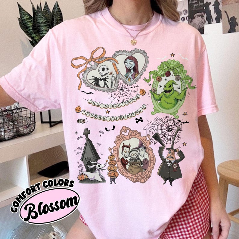May include: Pink Comfort Colors t-shirt featuring illustrations from "The Nightmare Before Christmas." The design includes Jack Skellington, Sally, Oogie Boogie, and other characters in ornate frames. The text "The Nightmare Before Christmas" is also present.