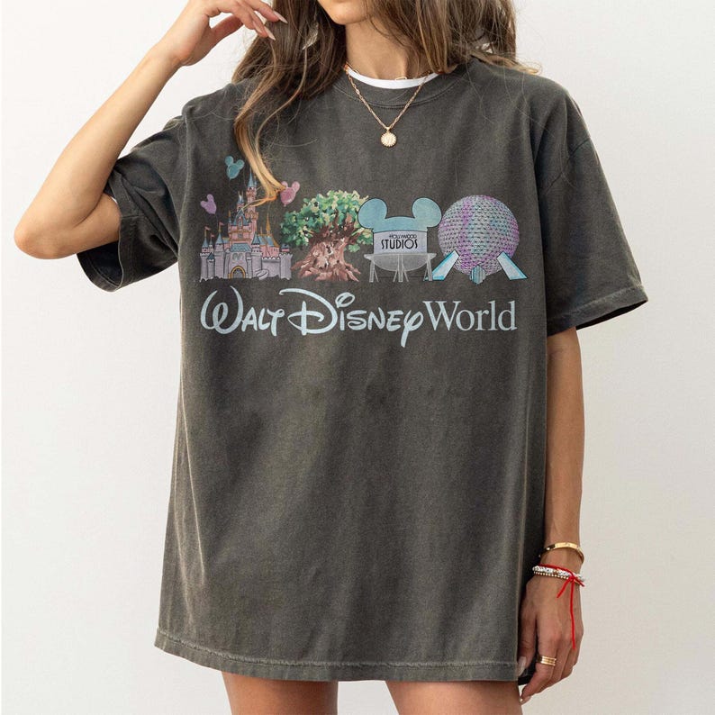 May include: Dark grey t-shirt with a Walt Disney World graphic. The design features a castle, tree, and Spaceship Earth, with the words "Walt Disney World". The shirt has a vintage, worn appearance.