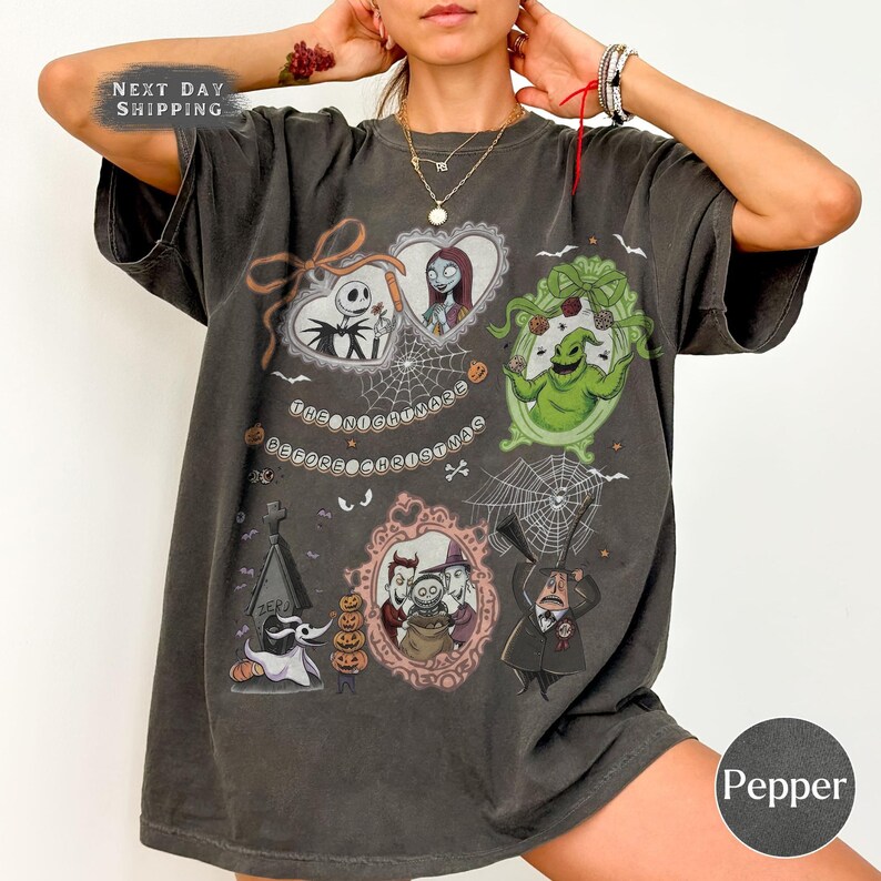 May include: Dark grey t-shirt featuring multiple framed images of characters from "The Nightmare Before Christmas." The shirt includes Jack Skellington, Sally, Oogie Boogie, and Zero. The text "The Nightmare Before Christmas" is also present.