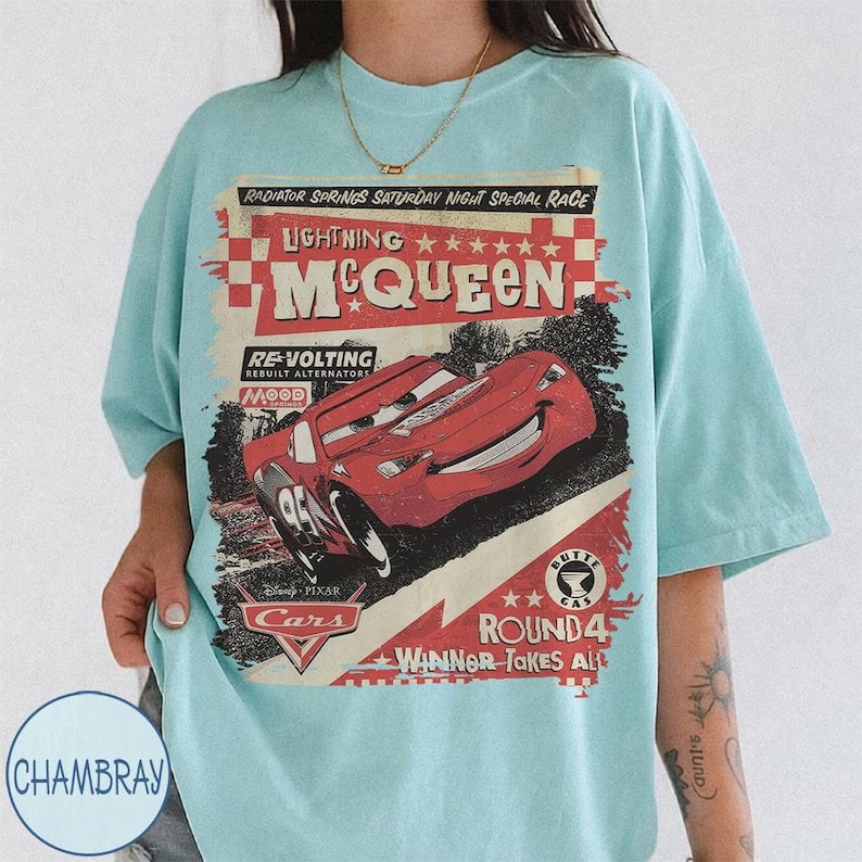 May include: Light blue t-shirt featuring a graphic of Lightning McQueen from the movie Cars. The design includes text that reads "Radiator Springs Saturday Night Special Race" and "Winner Takes All". The shirt has a vintage, distressed look.