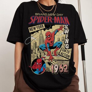 Puede incluir: Camiseta negra con un dise&ntilde;o vintage de Spider-Man. El dise&ntilde;o incluye las palabras "Brand New Day", "Spider-Man" y "New York", junto con una ilustraci&oacute;n de Spider-Man y el a&ntilde;o 1962.
