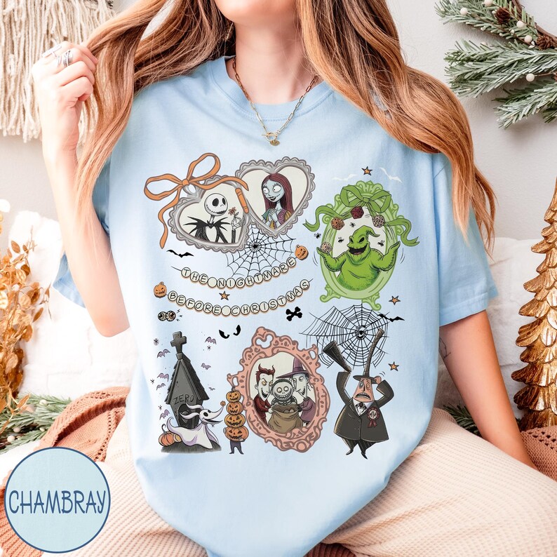May include: Light blue t-shirt featuring framed illustrations of characters from "The Nightmare Before Christmas." The design includes Jack Skellington, Sally, Oogie Boogie, and other characters, with the text "The Nightmare Before Christmas."
