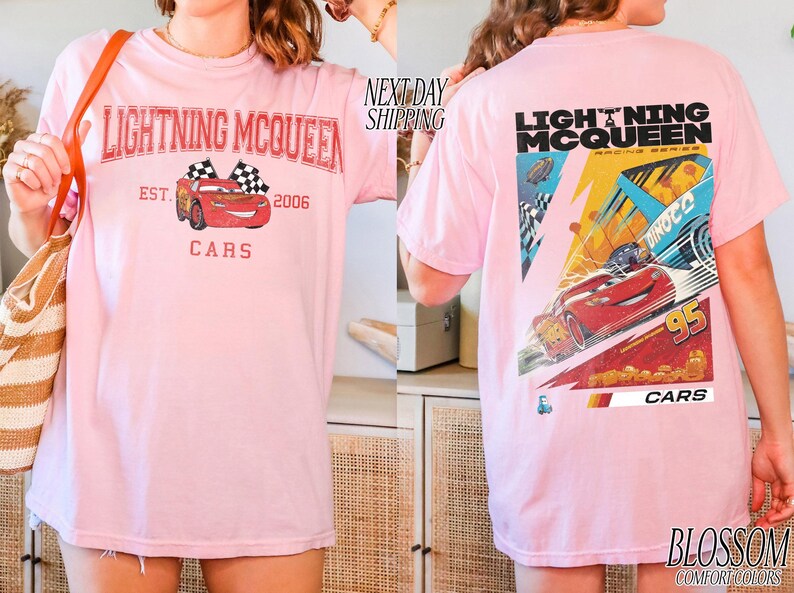 May include: Light pink t-shirt featuring Lightning McQueen from the Cars movie. The front graphic shows McQueen with checkered flags and text. The back displays a larger graphic of McQueen racing, with the number 95 and the word "CARS".