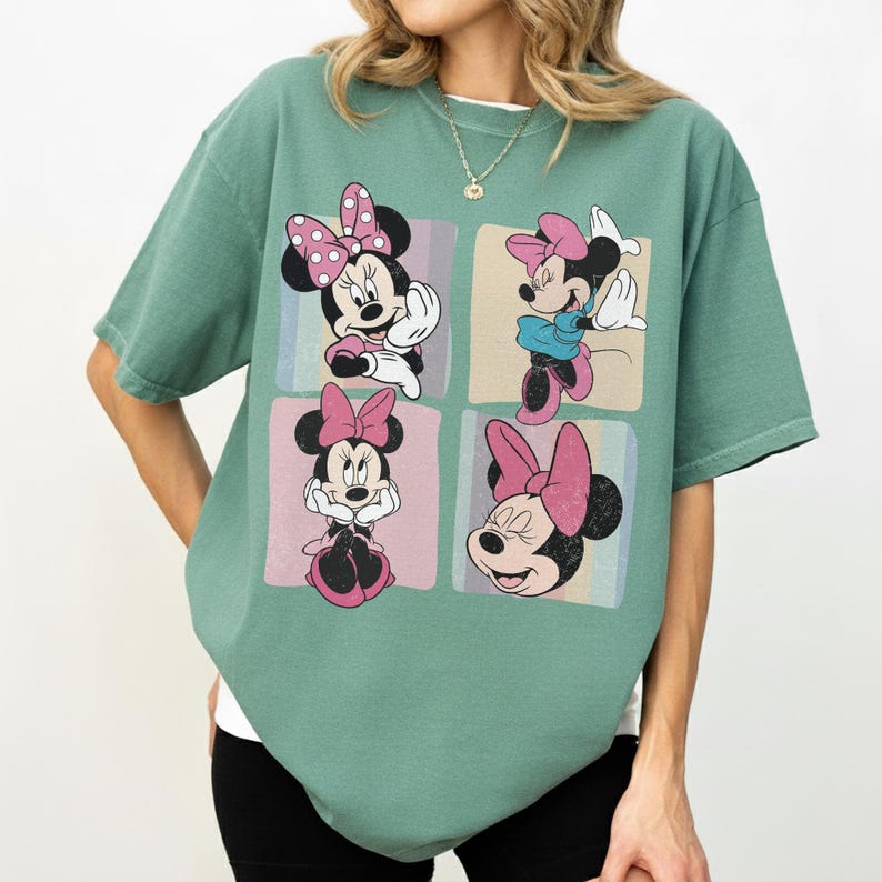 Op de afbeelding: Een groen t-shirt met vier afbeeldingen van Minnie Mouse. Elke afbeelding staat in een pastelkleurig vierkant. Minnie Mouse wordt getoond met haar kenmerkende roze strik in verschillende poses. Het shirt heeft korte mouwen en een relaxte pasvorm.