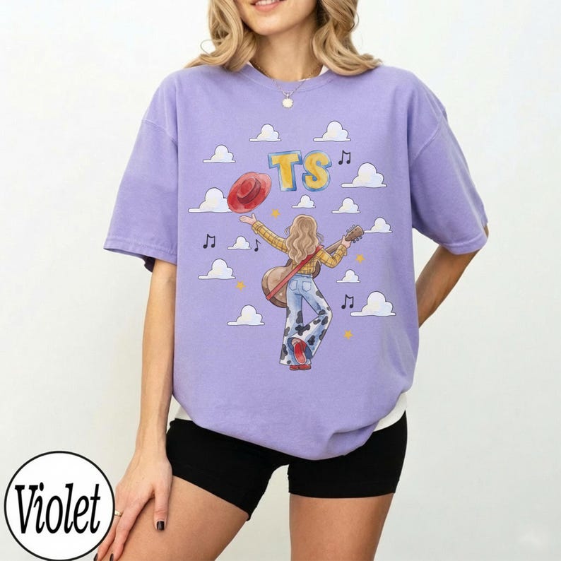 May include: A violet short-sleeve t-shirt featuring a graphic of a person with long blonde hair playing an acoustic guitar, wearing a yellow plaid shirt and cow-print bell-bottom pants, holding a red hat, with clouds, music notes, and the text TS.