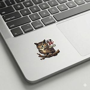 以下が含まれることがあります： 茶色のフクロウが枝に止まっている詳細なイラストのステッカー。フクロウは黄色い目を持ち、「WISE」の文字と日本語の文字が書かれています。ステッカーはラップトップに貼られています。