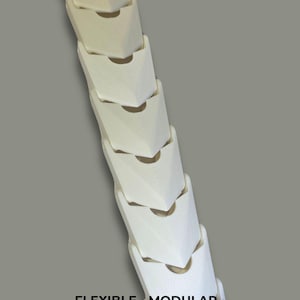 May include: A white, modular, snap-together dragon spine featuring a series of interlocking, textured segments. The text SNAP TOGETHER DRAGON SPINE is at the top, and FLEXIBLE &bull; MODULAR &bull; WEARABLE is printed at the bottom of this articulated piece.