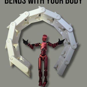 May include: A white, multi-segmented, articulated plastic structure that curves into a semi-circle, positioned behind a small, metallic red humanoid action figure with black joints. The text BENDS WITH YOUR BODY is printed in black at the top.