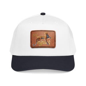 Puede incluir: Gorra de béisbol blanca con visera azul marino y botón negro. La gorra presenta un parche de cuero marrón con una ilustración detallada de un leopardo descansando sobre una rama. El leopardo tiene un pelaje manchado y se encuentra sobre un fondo de follaje estilizado.