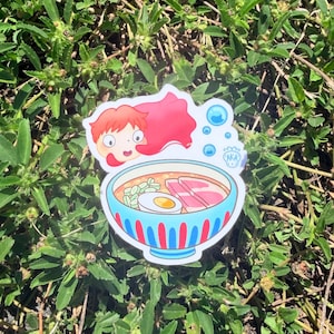 Puede incluir: Una pegatina con un personaje de dibujos animados con pelo rojo y un cuenco de ramen. El cuenco azul tiene rayas rojas y contiene fideos, un huevo y carne. Tambi&eacute;n hay burbujas y el texto "(AKA)".
