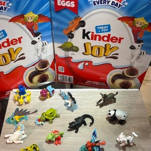 May include: Kinder Joy egg packaging with the text "20 Eggs" and "A Surprise Every Day." The image shows various toy figurines, including a zebra, a car, and a turtle. Other colorful creatures are also visible.